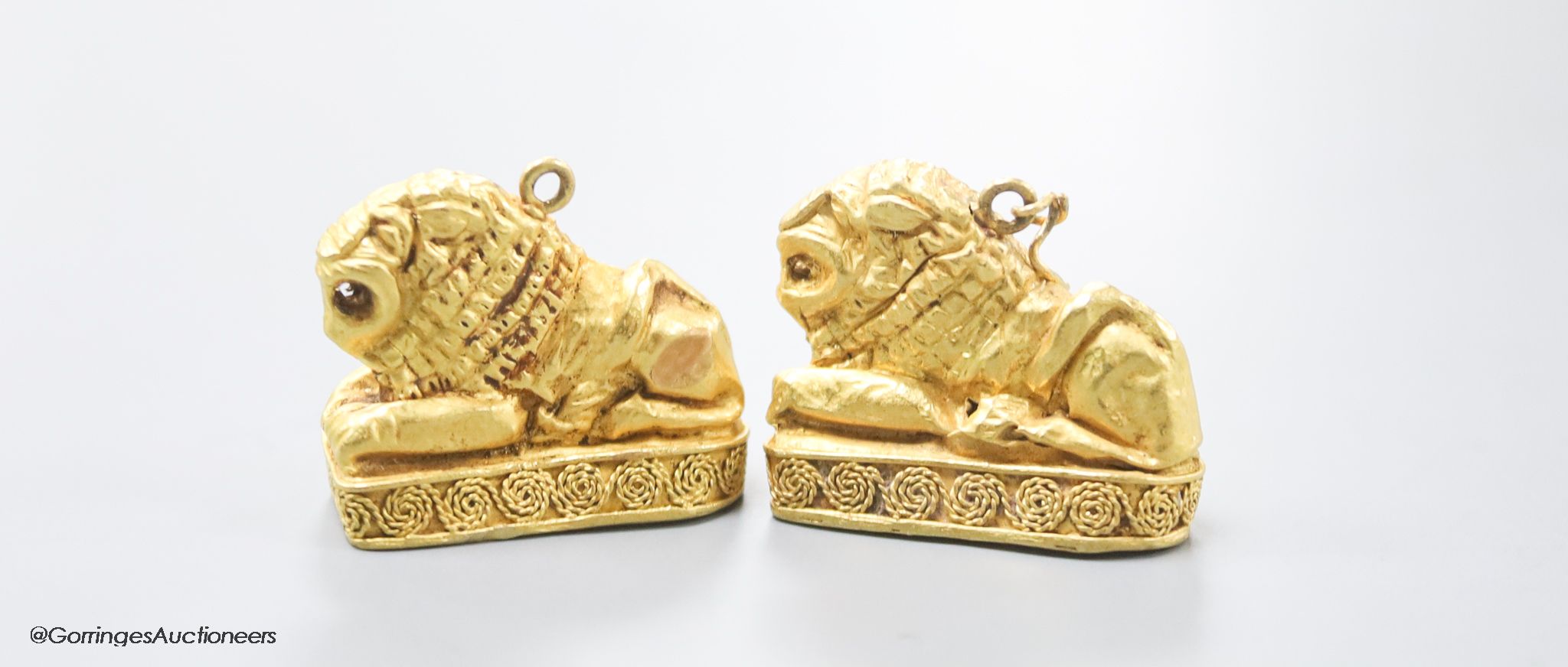 A pair of Etruscan style yellow metal recumbent lion pendant charms, 25mm, gross 11.1 grams (tests as 22ct)